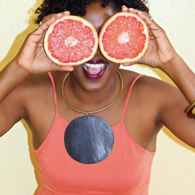 black woman with 2 half grapefruits covering eyes